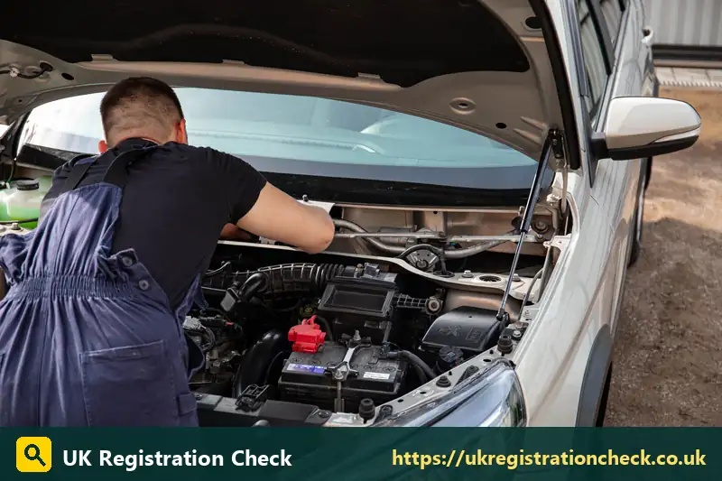 Mechanic checking the battery and engine of a silver car - cancellations mot
