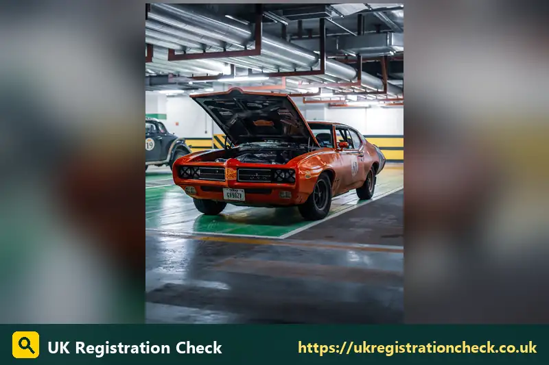 Classic orange muscle car in a garage with the bonnet up - private reg generator