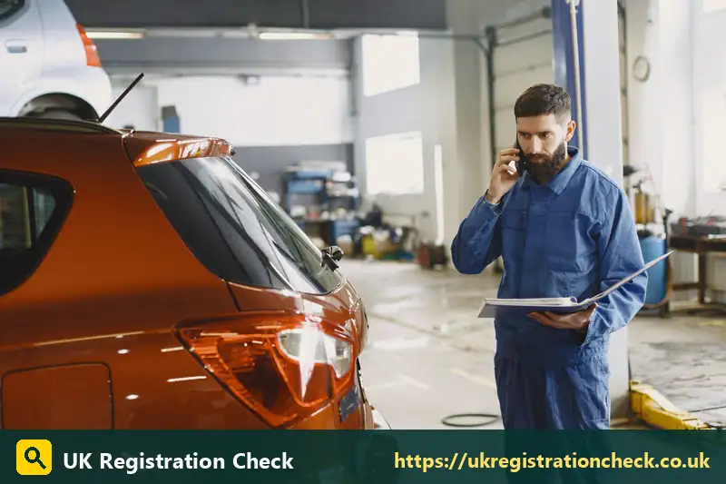 Mechanic with a clipboard on the phone in a garage - temporary car tax