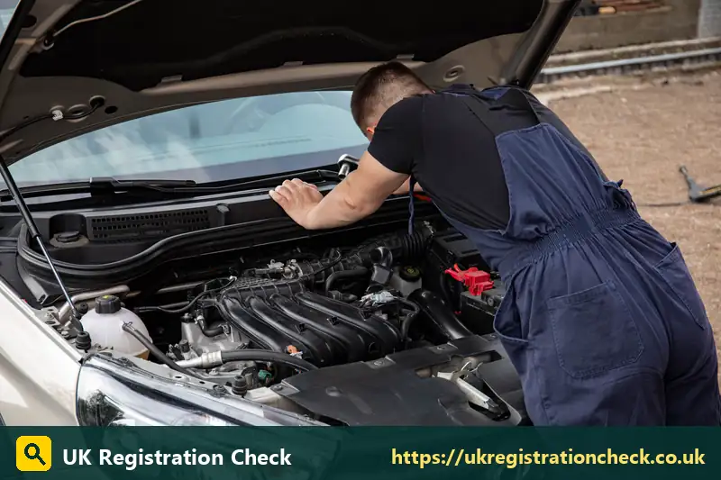 Mechanic in blue overalls inspecting a car engine - ulez check glasgow