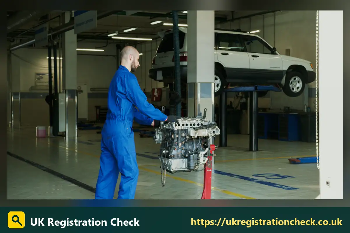 Mechanic carrying an engine in a garage with a car on a lift - change mot date