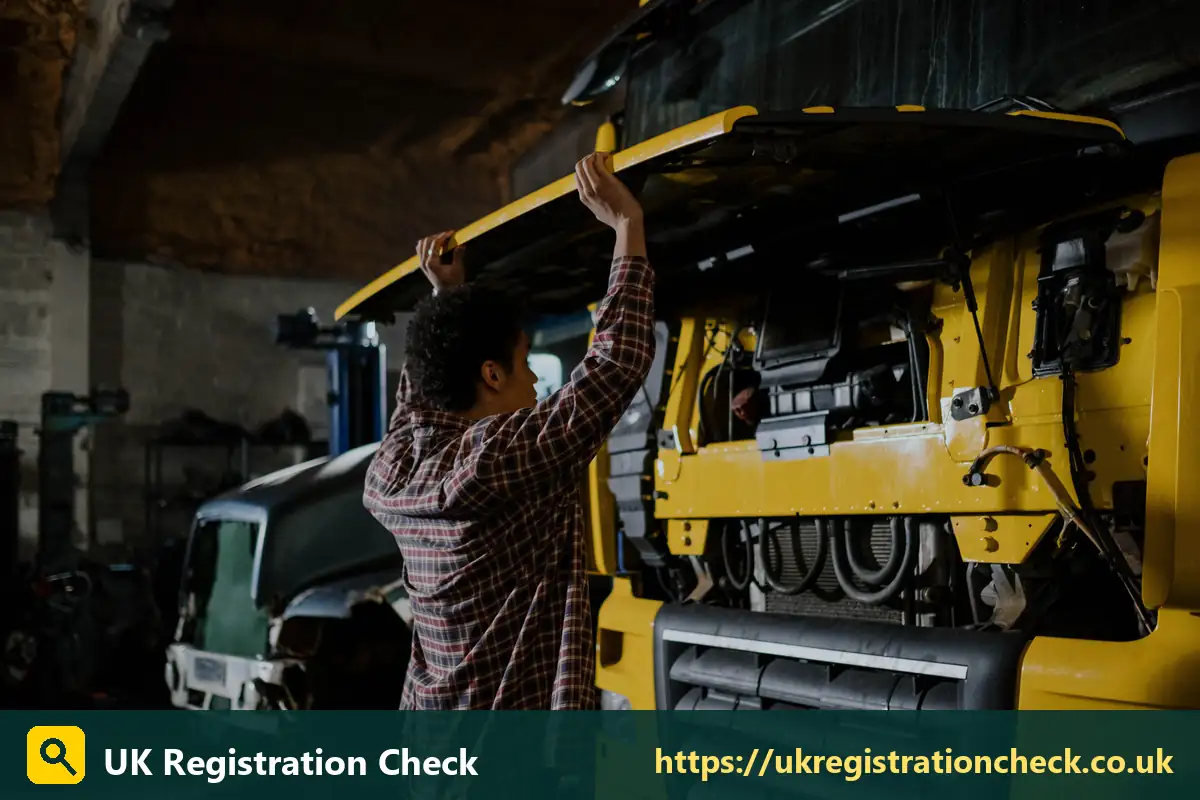 Mechanic checking under the cab of a yellow lorry - commercial vehicle tax